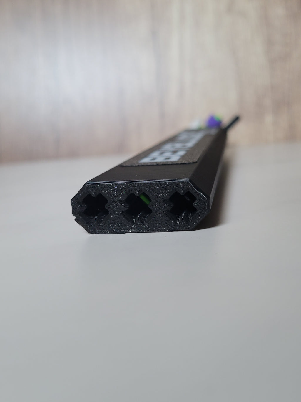 Close-up of the protector end with three X-pattern channel openings and a flush logo panel along the top.