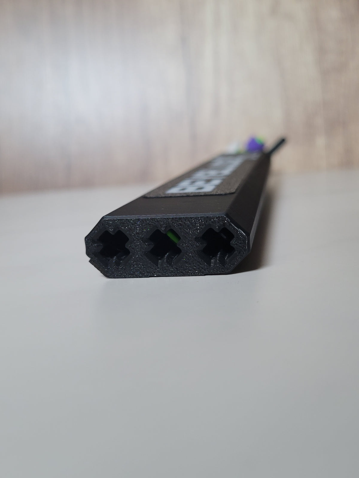 Close-up of the protector end with three X-pattern channel openings and a flush logo panel along the top.