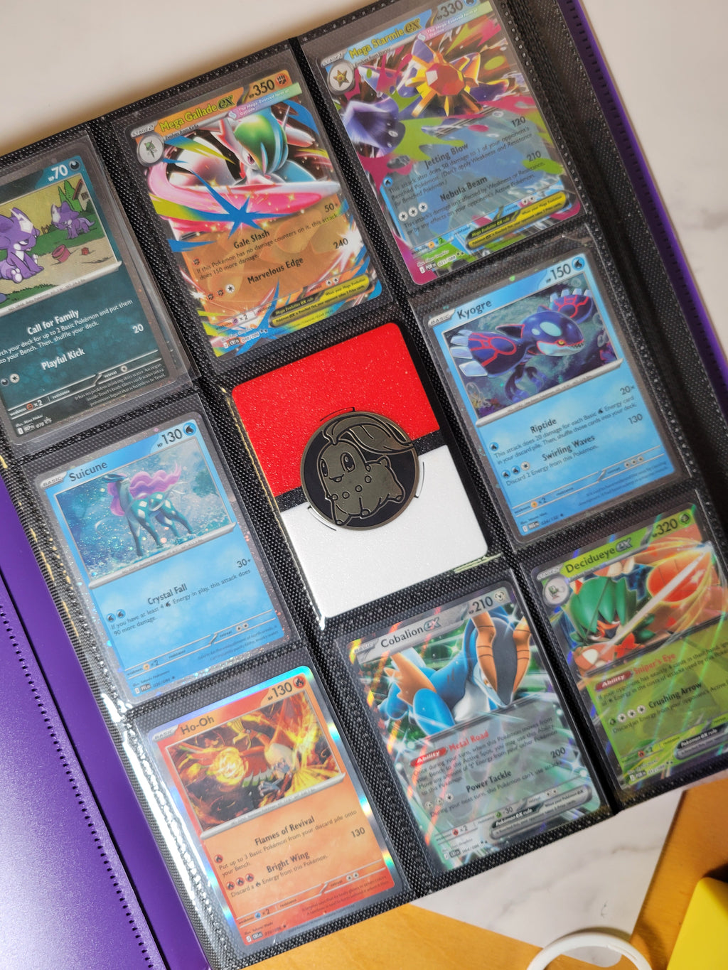 Coin display with a Pokémon coin seated in a trading-card binder pocket among Pokémon cards.