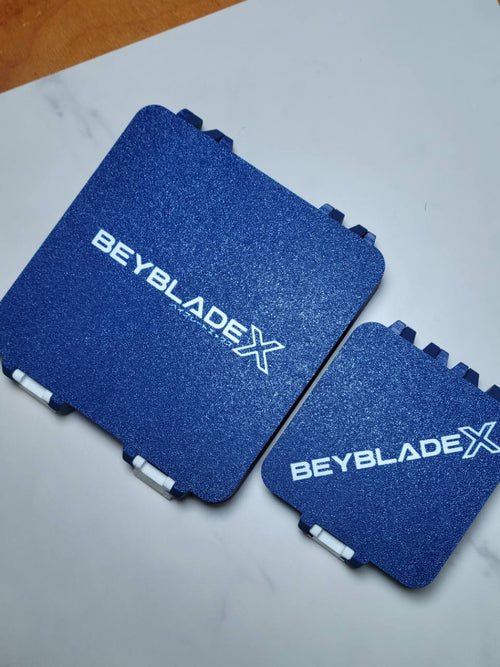 Blue and white 64-slot and 25-slot Beyblade X Bit Boxes shown side by side.
