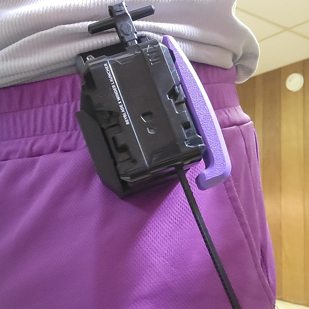 Black launcher carried in a purple Ruzz3D holster on a belt.