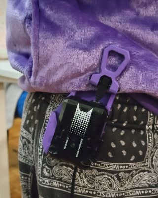 Black launcher mounted to a purple Ruzz3D holster on a belt.