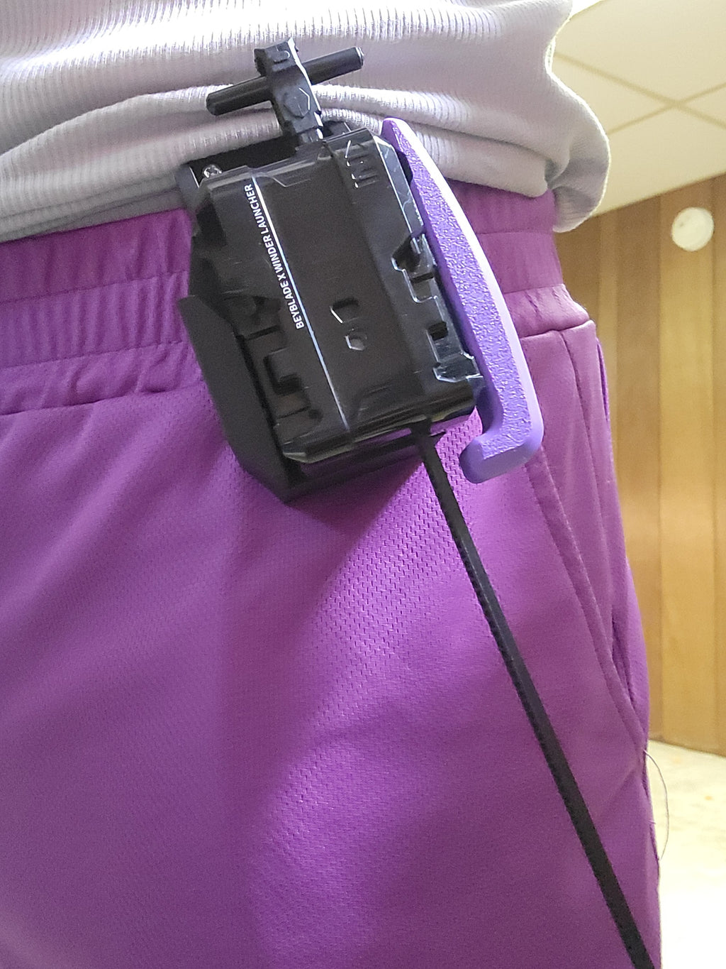 Purple launcher holster worn on a belt.