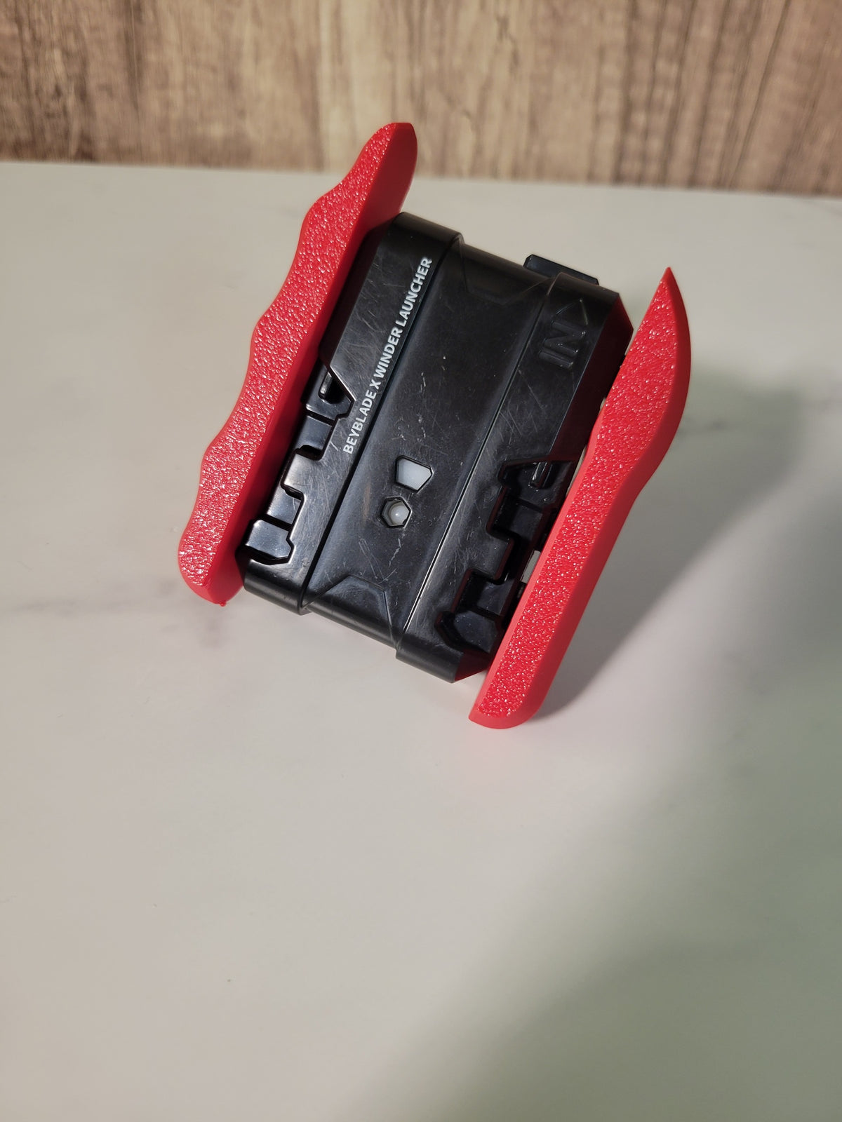 Underside of a red string launcher showing the attached grip.