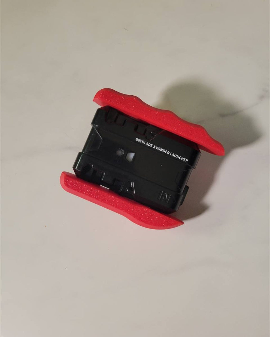 Bottom view of a black and red launcher setup with Ruzz3D grip.