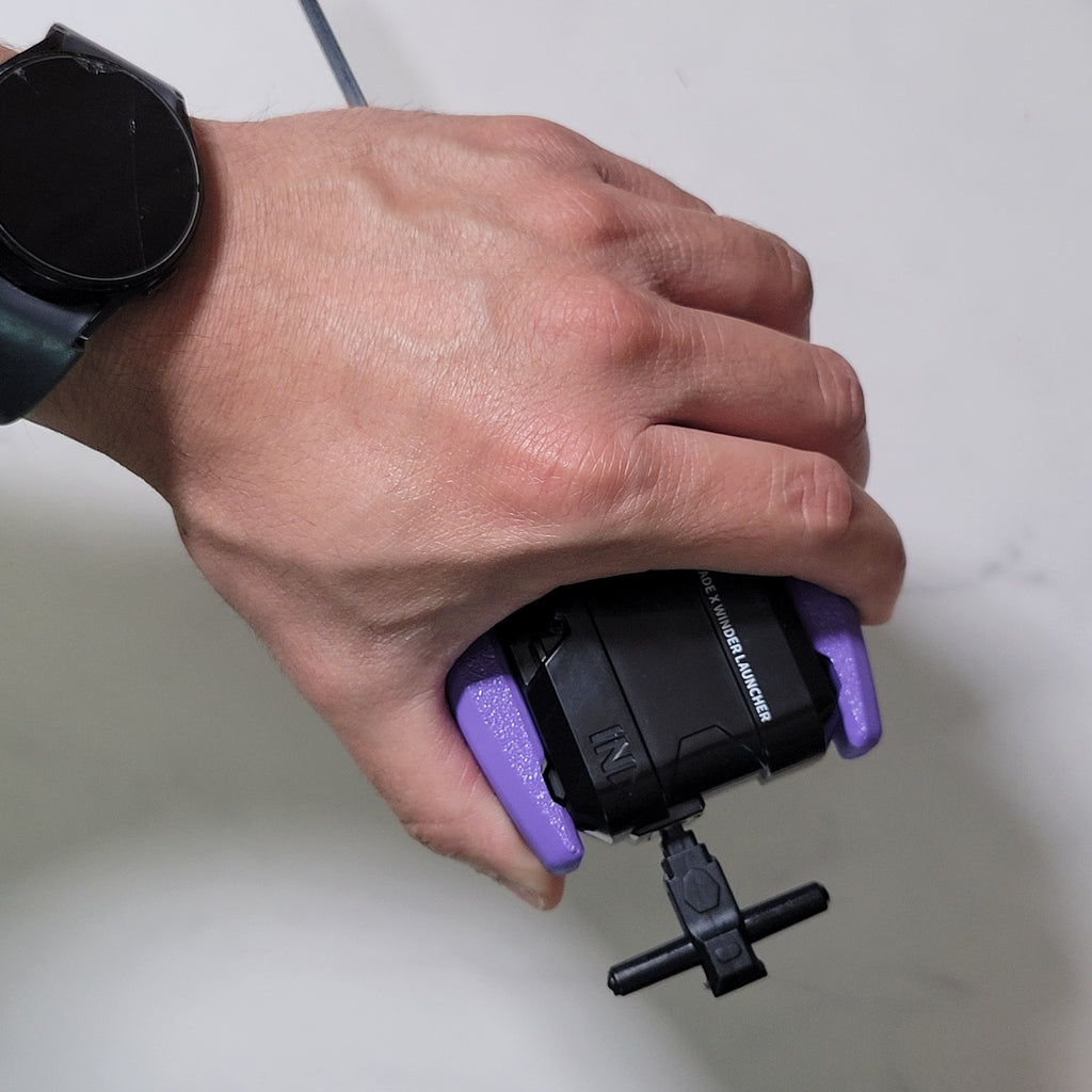 Hand holding the purple winder launcher grip with rip cord extended.