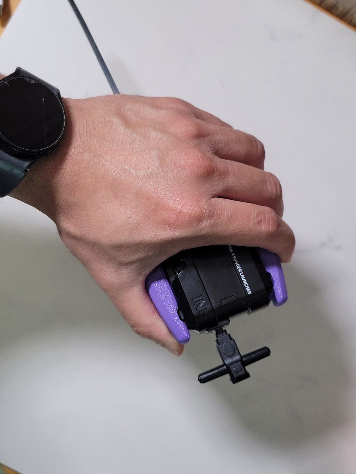 Hand holding a purple winder launcher grip.