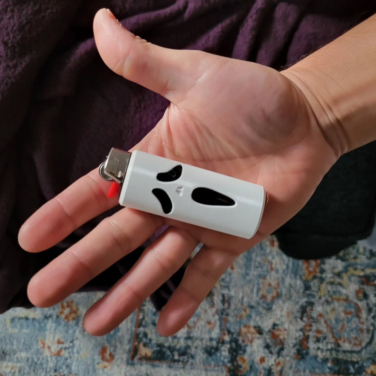 White Ghostface-inspired lighter cover held in a hand.