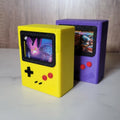 Yellow and purple Game Boy Color-inspired TCG deck boxes with front card display windows by Ruzz3D.