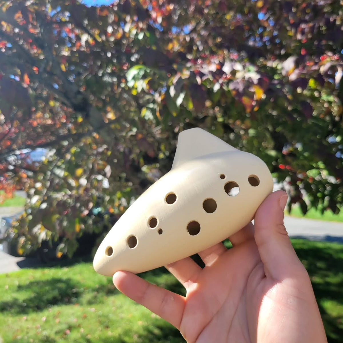 Front view of the ocarina held in a hand, with its finger-hole layout visible.