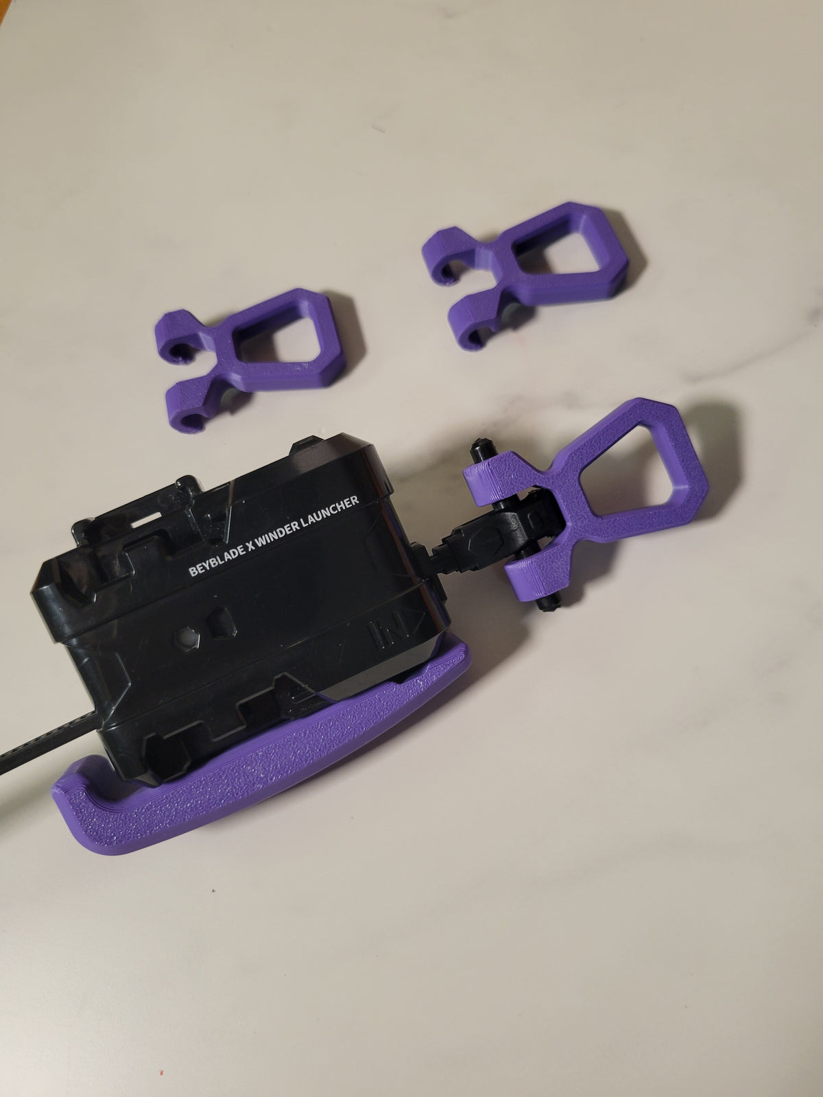Purple pull grips shown beside a launcher for context; one grip supplied, launcher not included